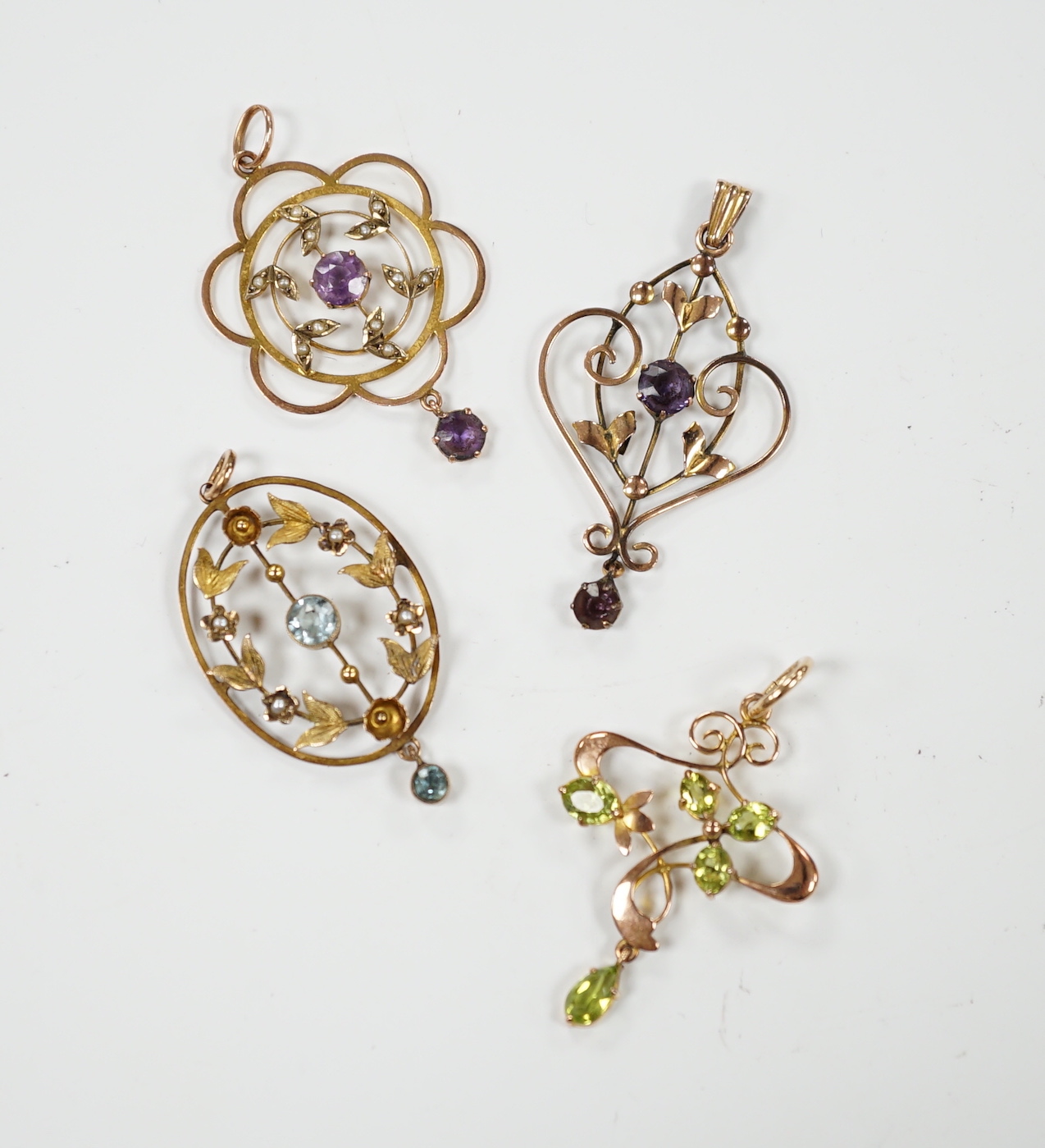 Three assorted early 20th century 9ct and gem set pendants, one other similar yellow metal and gem set pendant, largest, 40mm, gross weight 7.5 grams.